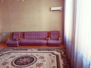 un divano viola in soggiorno con tappeto di KOSHGARI APARTMENT a Samarkand