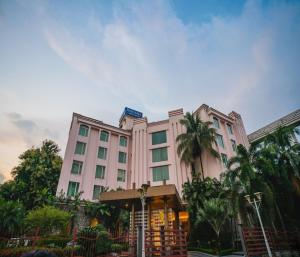 un grand bâtiment blanc avec des palmiers devant lui dans l'établissement Barsana Hotel & Resort Siliguri, à Siliguri