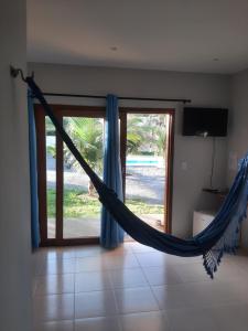 uma rede de descanso num quarto com uma porta de vidro deslizante em Pousada Casa du Soleil Camocim em Camocim