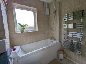 a bathroom with a bath tub and a window at Cosy house with a garden in London