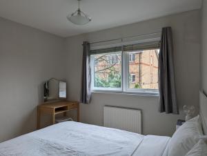 a bedroom with a white bed and a window at Cosy house with a garden in London