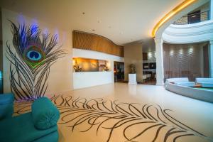 una sala de estar con un mural de plumas de pavo real en la pared en Barsana Hotel & Resort Siliguri, en Siliguri