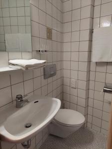 a white bathroom with a toilet and a sink at Gasthaus zur Krone in Weisenbach +12 photos