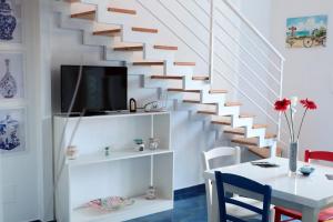 uma sala de estar com uma escada branca com uma mesa e uma televisão em sea home em Bacoli