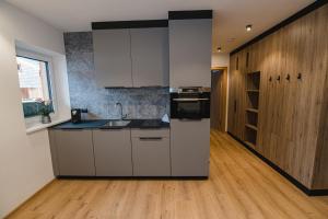 a kitchen with white cabinets and a wooden floor at Winkler Appartements in Saalbach Hinterglemm