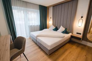 a bedroom with a bed and a chair and a window at Winkler Appartements in Saalbach Hinterglemm