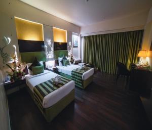 Barsana Hotel & Resort Siliguri في سيليغري: غرفة فندقية بسريرين واريكة