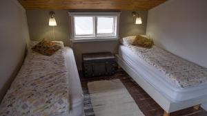 2 camas en una habitación pequeña con ventana en Hótel Djúpavík en Djupavik