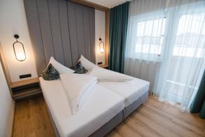 a bedroom with a white bed and a large window at Winkler Appartements in Saalbach Hinterglemm