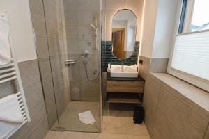 a bathroom with a shower and a sink and a mirror at Winkler Appartements in Saalbach Hinterglemm