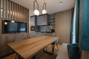 a dining room with a wooden table and a kitchen at Winkler Appartements in Saalbach Hinterglemm