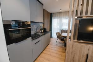a kitchen with white cabinets and a flat screen tv at Winkler Appartements in Saalbach Hinterglemm