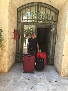 mężczyzna stojący w drzwiach z bagażem w obiekcie Appartamento bello e elegante in west Amman w mieście Amman
