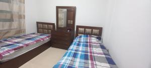 a bedroom with two beds and a dresser and a mirror at Appartamento bello e elegante in west Amman in Amman