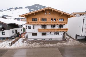 a large wooden building with snow in front of it at Winkler Appartements in Saalbach Hinterglemm
