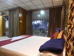een slaapkamer met een bed en een groot raam bij The Andaman Sunset View Resort in Port Blair