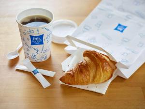 uma mesa com uma chávena de café e um croissant em Ibis budget Béziers Est Mediterranée A9 / A75 em Béziers