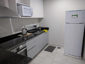 uma cozinha branca com um frigorífico e um micro-ondas em Impecable y nuevo, zona aeropuerto! em Assunção