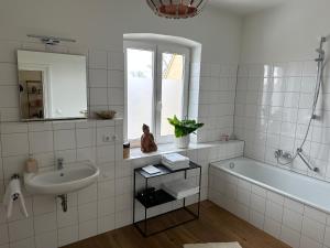 Baño blanco con bañera y lavamanos en Mühlbach´s, en Kaufbeuren