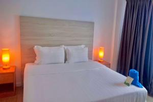 a bedroom with a large white bed with two lamps at Ramada by Wyndham Langkawi Marina in Kuah