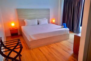 a bedroom with a white bed with two lamps at Ramada by Wyndham Langkawi Marina in Kuah