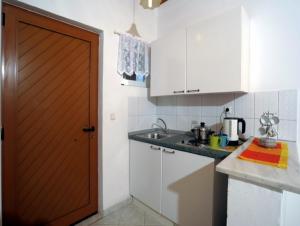 a kitchen with white cabinets and a wooden door at Ferienhaus Elena in Agios Georgios +11 photos
