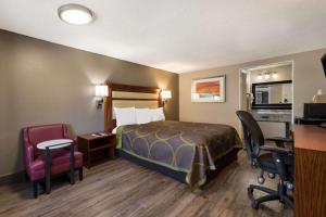 シャーロットにあるRodeway Inn Charlotte Airport Areaのベッド、デスク、椅子が備わるホテルルームです。