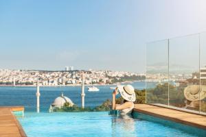 una mujer en una piscina con vistas al agua en The Ritz-Carlton, Istanbul at the Bosphorus, en Estambul