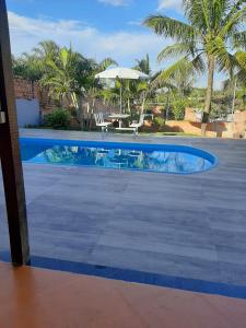 a swimming pool with a table and an umbrella at Chacara Oliva in Piracicaba