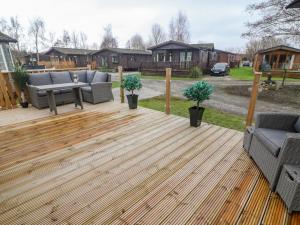 a wooden deck with two couches and a table at Lindale Lodge in Carnforth
