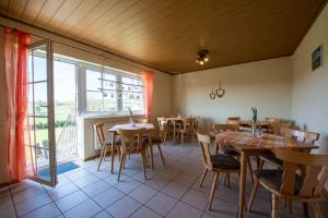 a restaurant with tables and chairs and a large window at Pension Oppelt in Rauhenebrach