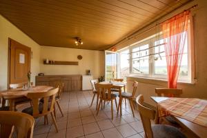 a dining room with tables and chairs and a kitchen at Pension Oppelt in Rauhenebrach