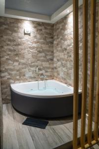 a bath tub in a room with a stone wall at Guesthouse Aelia in Kato Loutraki