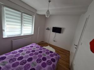 a bedroom with a purple bed and a window at Apartman CRYSTAL in Brčko