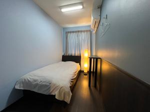 Dormitorio pequeño con cama y luz en Hotel Sunplaza 2, en Osaka