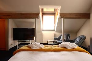 a bedroom with a bed with two chairs and a tv at La Clef D'Or Auberge Communale in Bursinel