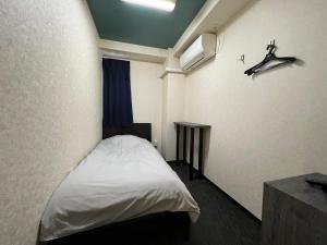 Un pequeño dormitorio con una cama blanca y una mesa en Hotel Sunplaza 2, en Osaka