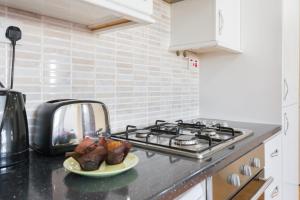 a kitchen with a stove and a plate of food at Comfortable Budget Apartment Next To Eurostar International - Kings Cross & Euston Station in London