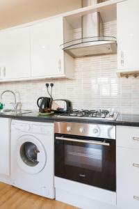 a kitchen with a stove and a washing machine at Comfortable Budget Apartment Next To Eurostar International - Kings Cross & Euston Station in London