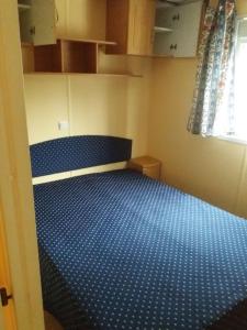 een kleine kamer met een blauw bed erin bij Bungalow au bord de la piscine 4 pers 5A in Burinhosa