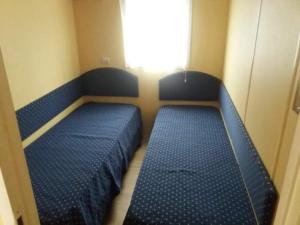 2 camas en una habitación pequeña con ventana en Bungalow au bord de la piscine 4 pers 5A en Burinhosa