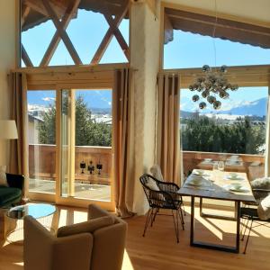 sala de estar con mesa, sillas y ventanas grandes en Loftwohnung mit Bergblick, en Saalfelden am Steinernen Meer