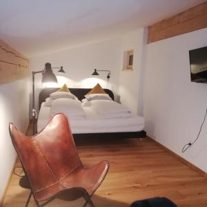 Un dormitorio con una cama y una silla dentro. en Loftwohnung mit Bergblick, en Saalfelden am Steinernen Meer