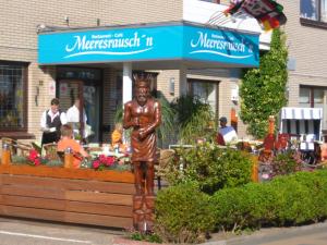 a statue of a man in front of a restaurant at Familien- und Aparthotel Strandhof in Butjadingen OT Tossens