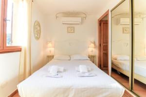 a bedroom with a white bed and a mirror at SELECT'SO HOME - Villa PANORAMA - Services hôteliers & prestations de qualité in Le Lavandou
