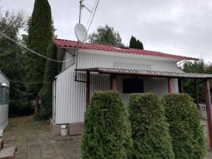 une maison blanche avec des buissons devant elle dans l'établissement Pod Sową, à Drawsko Pomorskie