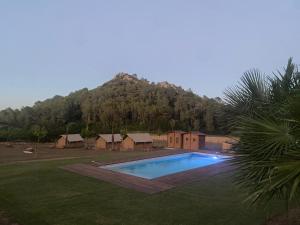 una piscina en un patio con una montaña en el fondo en Glamping VALL de CODÓ en Terrades