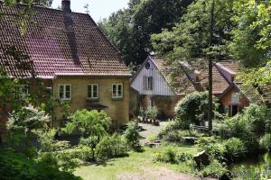 une maison ancienne avec un jardin en face dans l'établissement Apartments Wassermühle Stenten, à Alt Duvenstedt