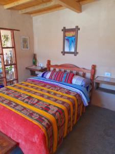 a bedroom with a bed with a colorful blanket at Sumaj Rústica in Maimará