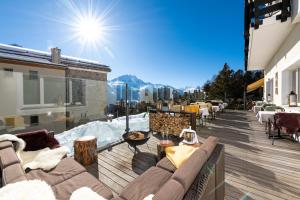 einen Balkon mit Sofas und Tischen auf einem Gebäude in der Unterkunft Berghotel Randolins in St. Moritz